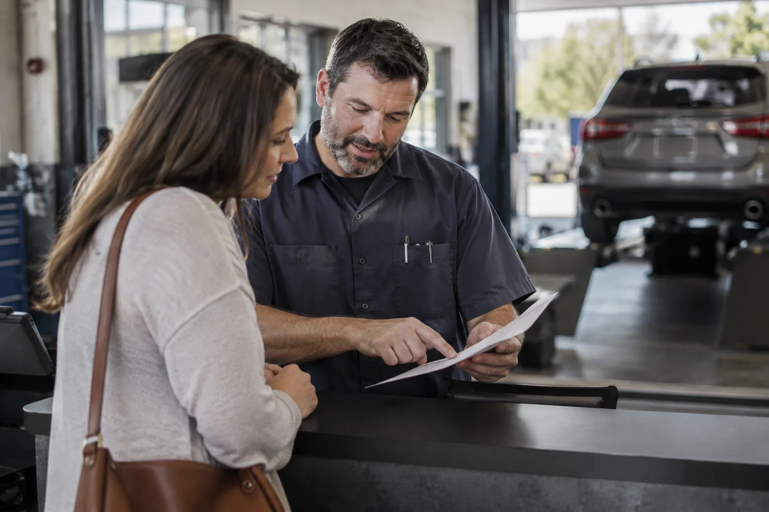 A technician explains smog test results to a customer at the service counter.
