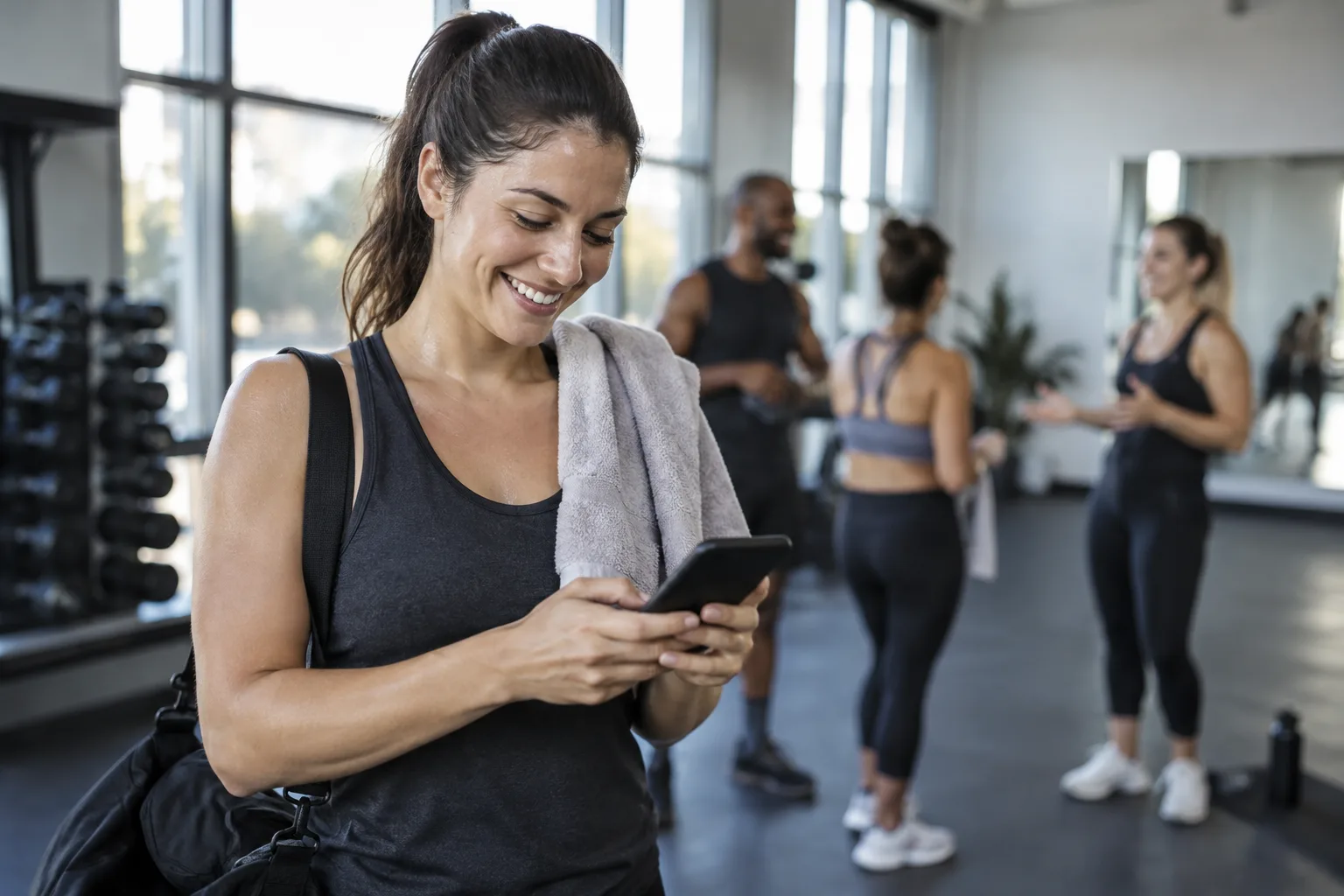 A photo of a satisfied gym member writing an online review on their phone after finishing a fitness class