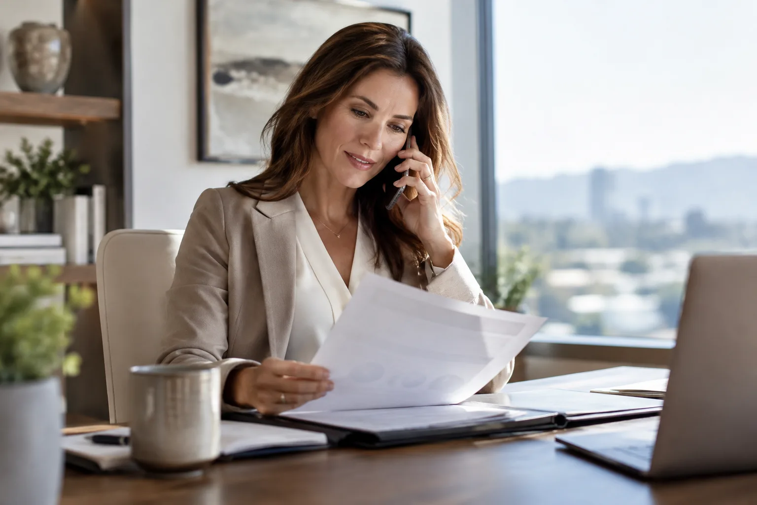 A salesperson on the phone reviewing a proposal document at their desk.